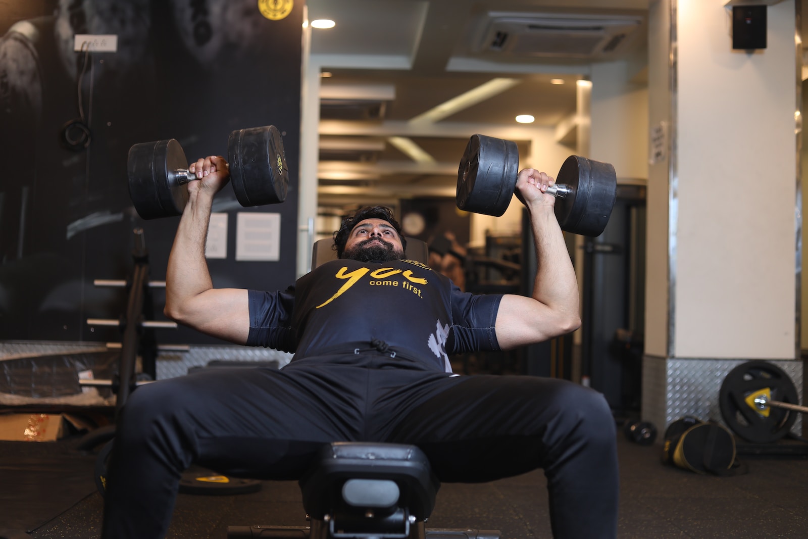 man in black and yellow adidas jersey shirt and black pants sitting on black exercise bench